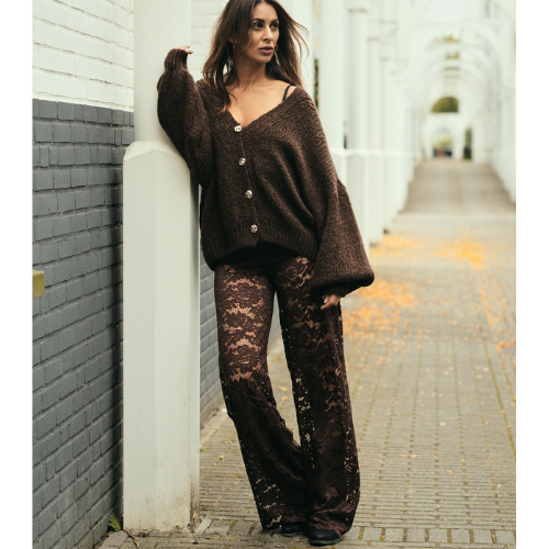 Model draagt de Lace Goddess Pants in bruin wijde kanten broek van Tesoros de Mujer.