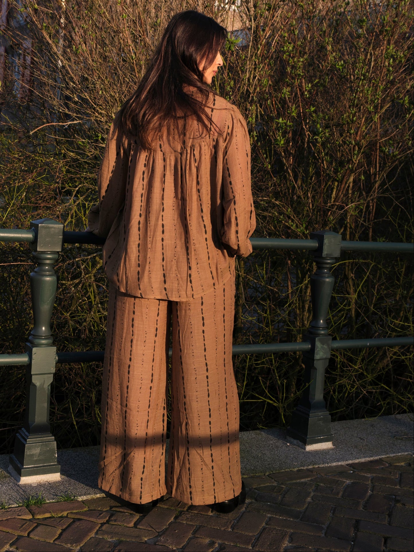 vrouw draagt bruin dames pak met zwarte print in buiten setting achterkant
