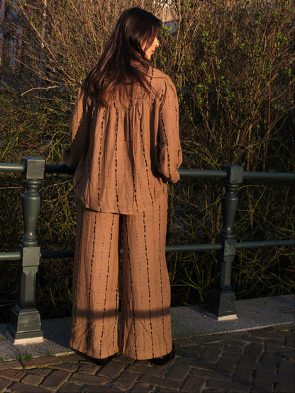 vrouw draagt bruin dames pak met zwarte print in buiten setting achterkant