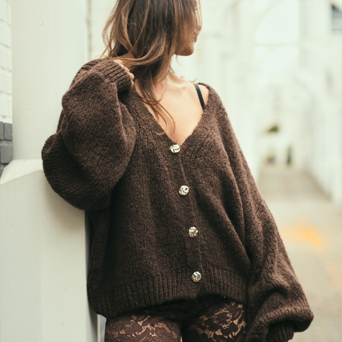 Close-up van de bruine Cozy Goddess Knit met grote knopen en luchtige textuur.