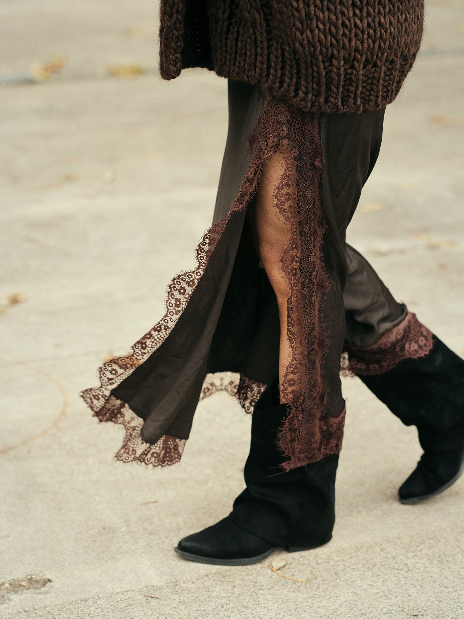 Detail van de kanten afwerking en hoge split van de bruine satijnen rok.